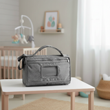 Gray diaper bag on a table in a nursery setting