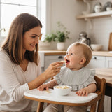 Baby wearing a beige cotton ruffle bib while being bottle-fed
