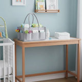 Wooden changing table with baby items against a light blue wall.