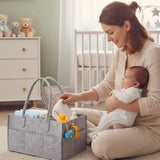 Woman holding a baby and a gray diaper bag in a nursery